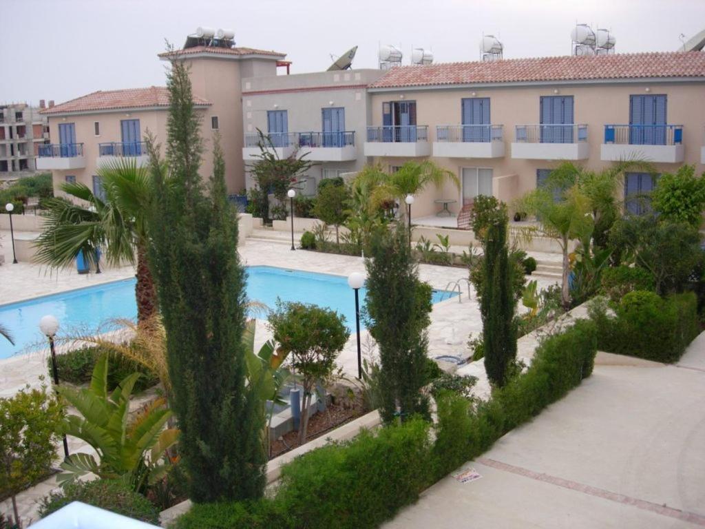 an apartment complex with a swimming pool and trees at Helios Cottages in Paphos City