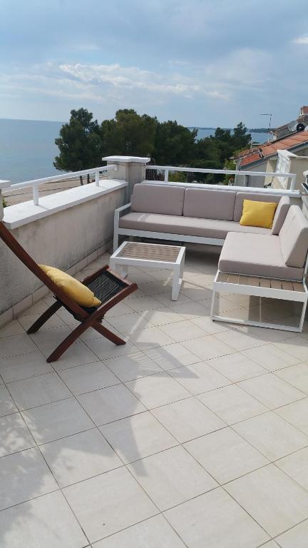 a patio with a couch and a chair on a roof at Apartments Lucija in Zadar