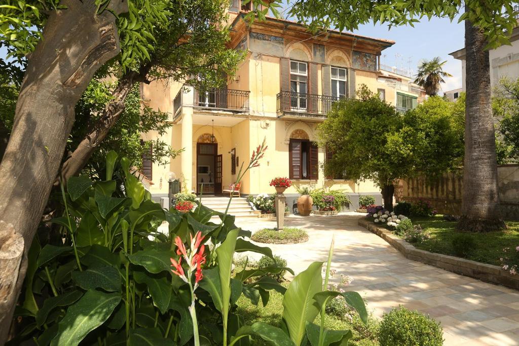 une grande maison jaune avec des arbres et des plantes dans l'établissement Villa Elide, à Vico Equense