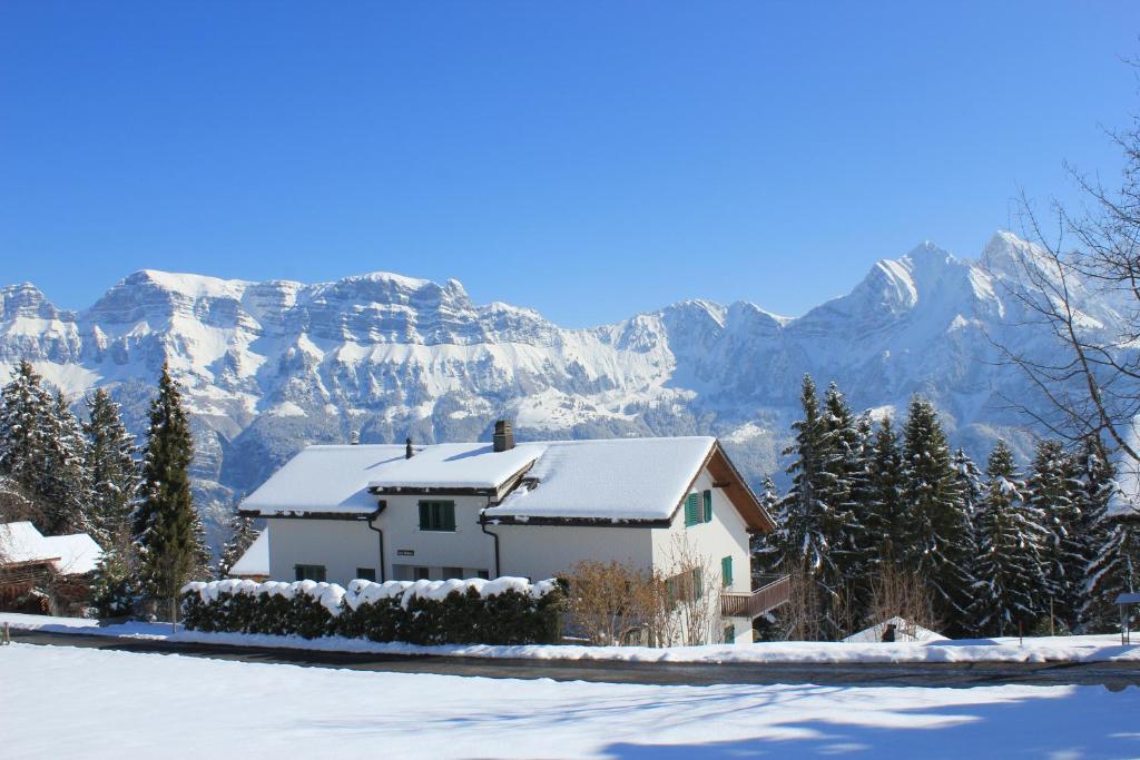 ein schneebedecktes Haus mit Bergen im Hintergrund in der Unterkunft Casa Malanca, Flumserberg in Flums