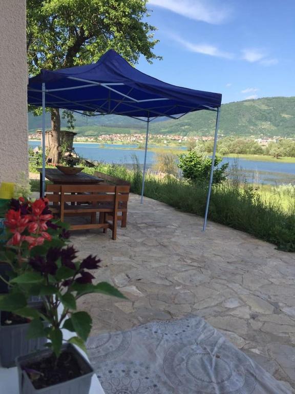 a blue umbrella over a bench and a lake at The Lakes Lagoon in Plav