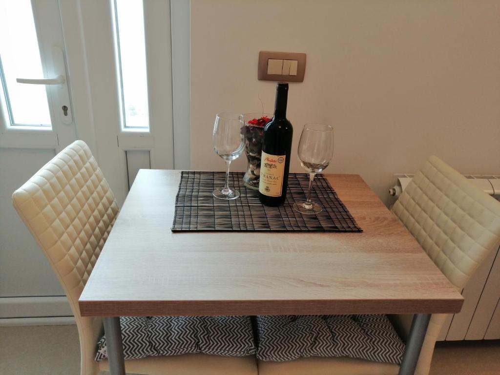 a table with a bottle of wine and two glasses at Studio Apartman Irena 2 in Bijela