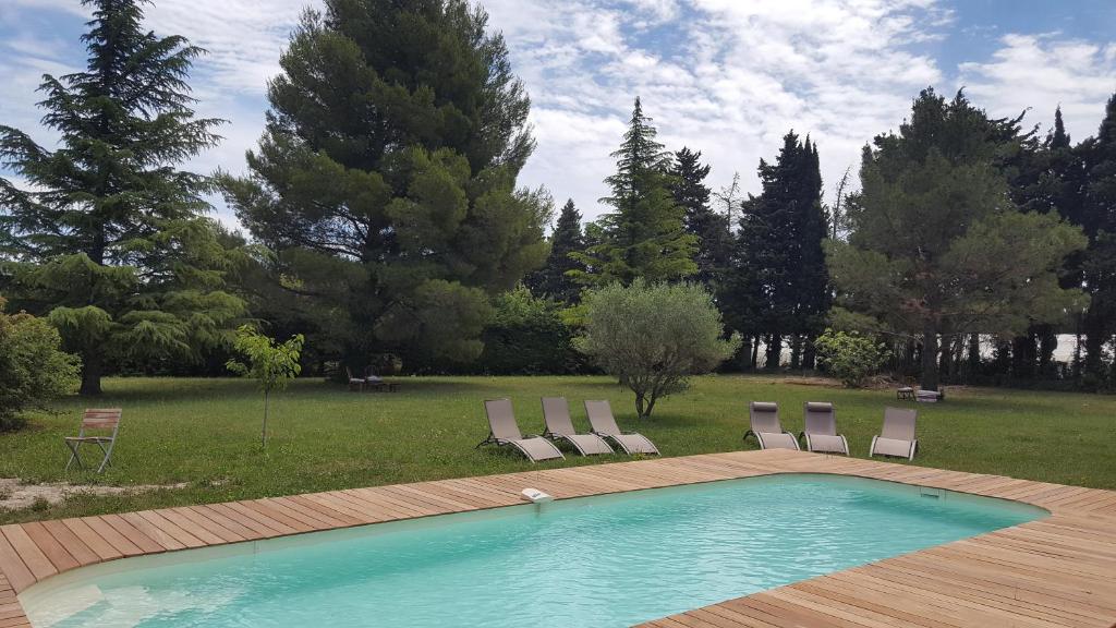 une piscine avec quatre chaises et une terrasse dans l'établissement LES CYPRES, à Maillane