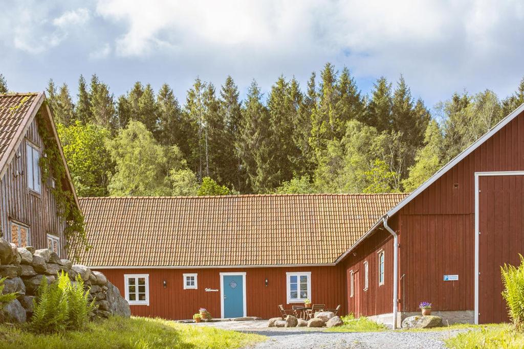 um celeiro vermelho com uma porta azul e árvores em Carpe Diem Sprängskulla em Veddige