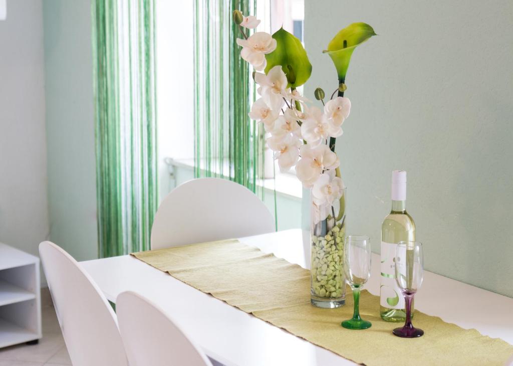 Apartment Ivana في ماكارسكا: طاولة مع زجاجة من النبيذ و مزهرية مع الزهور