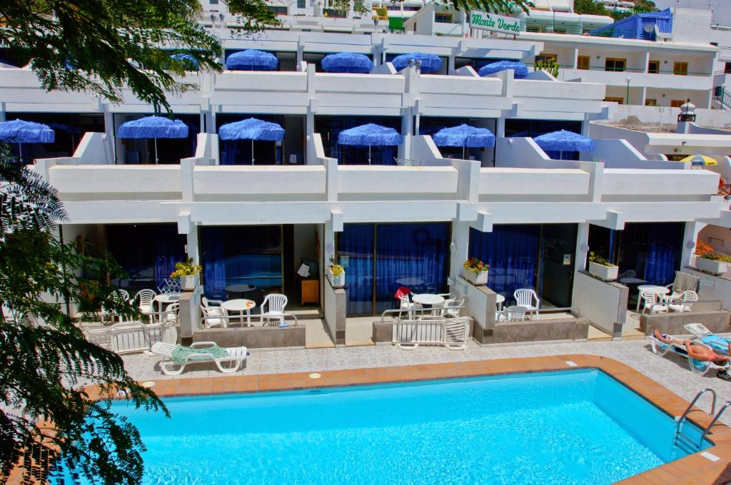 un hotel con piscina di fronte a un edificio di Apartamentos Monte Verde a Puerto Rico de Gran Canaria