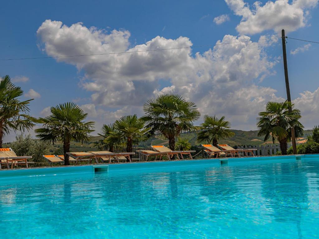 a large swimming pool with chairs and palm trees at Agriturismo Contea di val d'amone in Brisighella