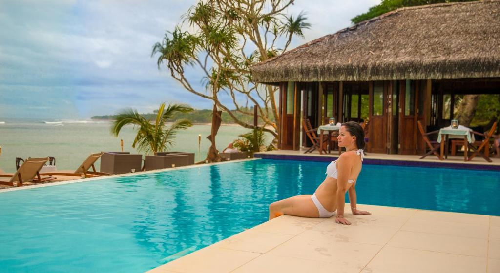 a woman in a bikini sitting on the edge of a swimming pool at Breakas Beach Resort in Port Vila