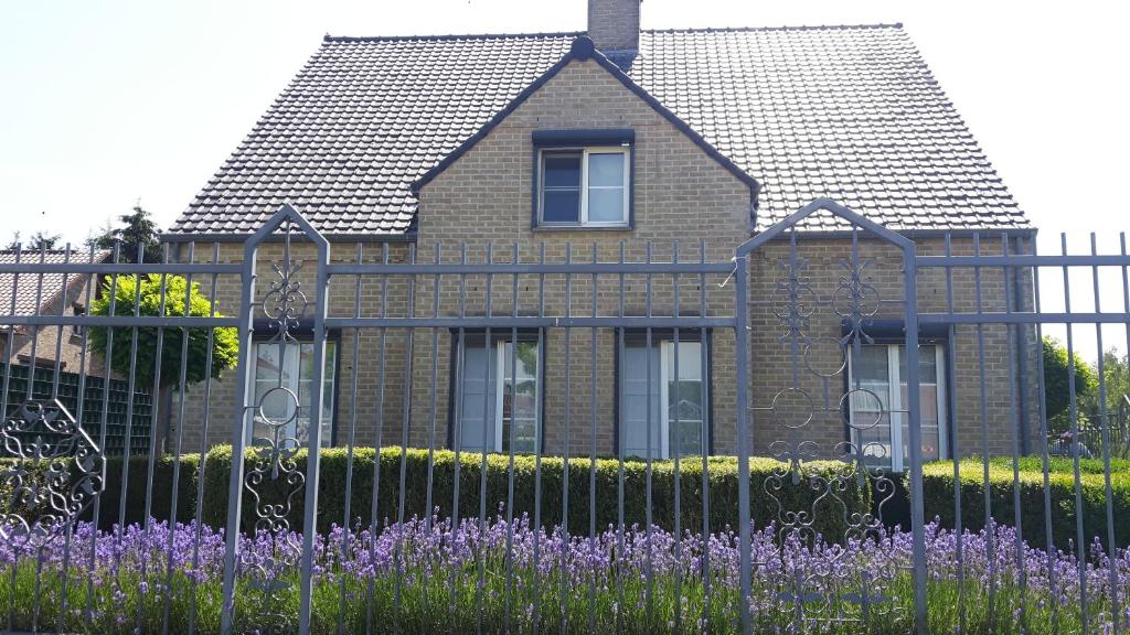uma casa atrás de uma cerca com flores roxas em Hemelse Helderheid em Maasmechelen