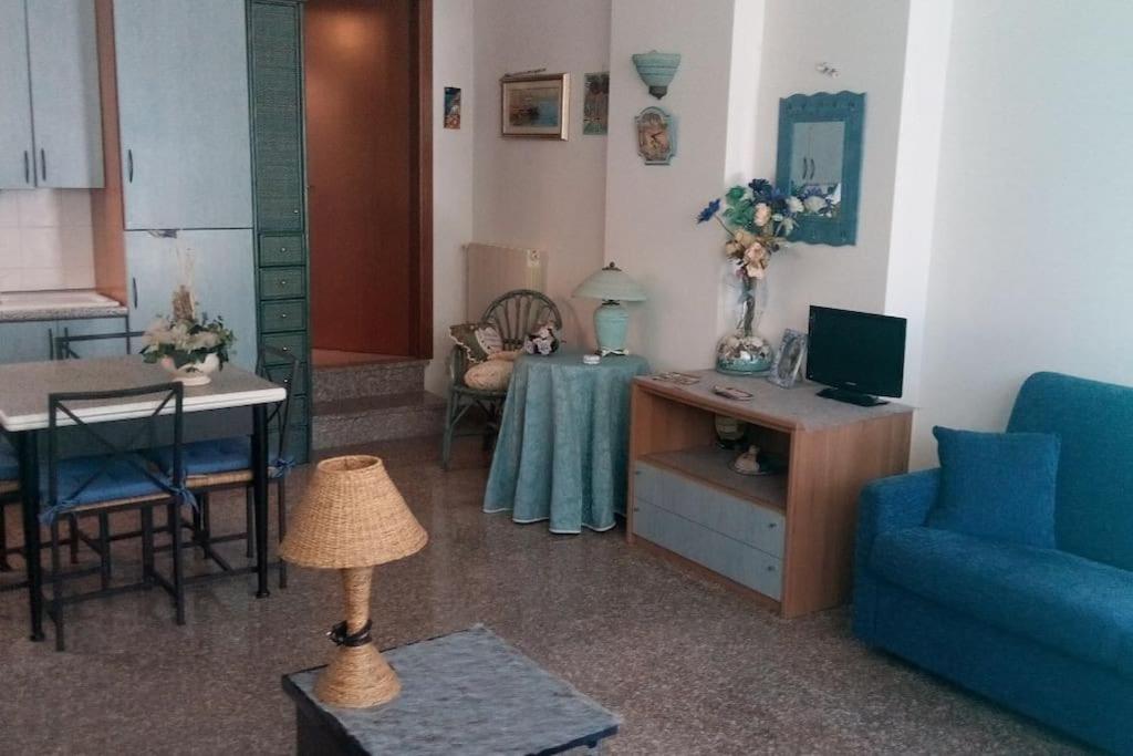 ein Wohnzimmer mit einem Tisch und einem blauen Sofa in der Unterkunft Piccola Bomboniera Sul Mare in Borgio Verezzi