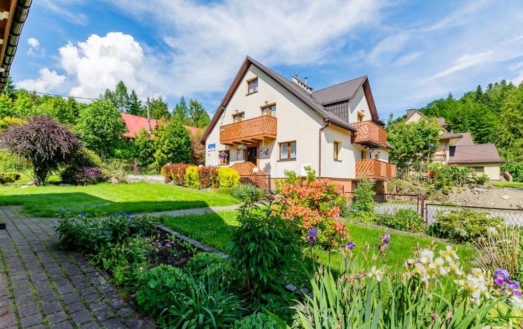 a house with a garden in front of it at Apartament i Pokoje Gościnne u Lusi in Wisła