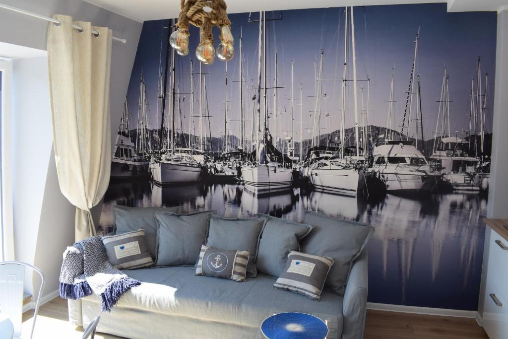 a living room with a couch with boats in a harbor at Apartament Silence Baltic Róża Wiatrów in Pobierowo