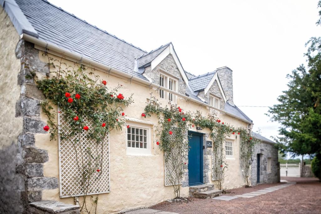 a house with red roses on the side of it at The Cheese House, Gileston Manor in Gileston