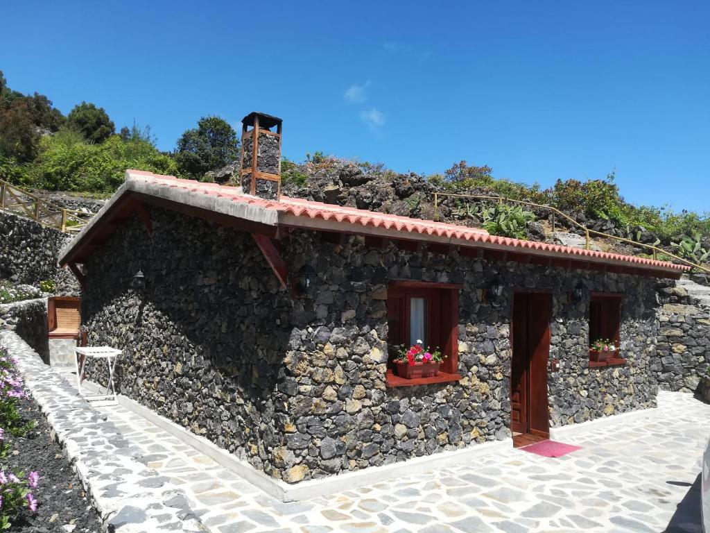 ein Steinhaus mit zwei Fenstern und einer Steinmauer in der Unterkunft Casas Rurales Los Guinderos in Icod de los Vinos