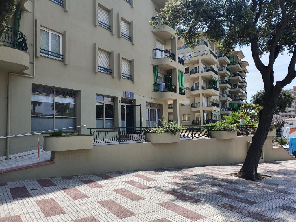 un edificio con balcones y un árbol delante de él en Faro SOLO para MUJERES, en Platja d'Aro