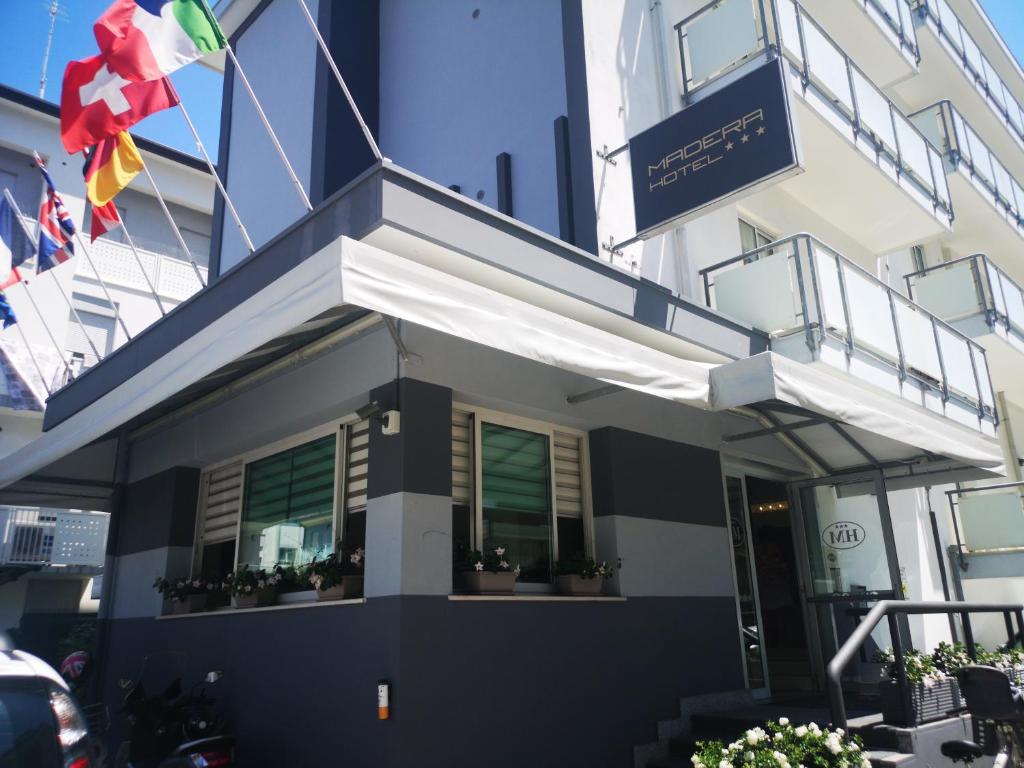 a facade of a building with potted plants and flags at Hotel Madera in Lido di Jesolo