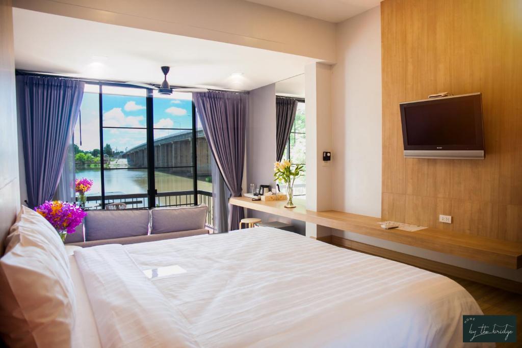 a bedroom with a bed and a tv and a window at Home by the Bridge - SHA Certified in Kamphaeng Phet