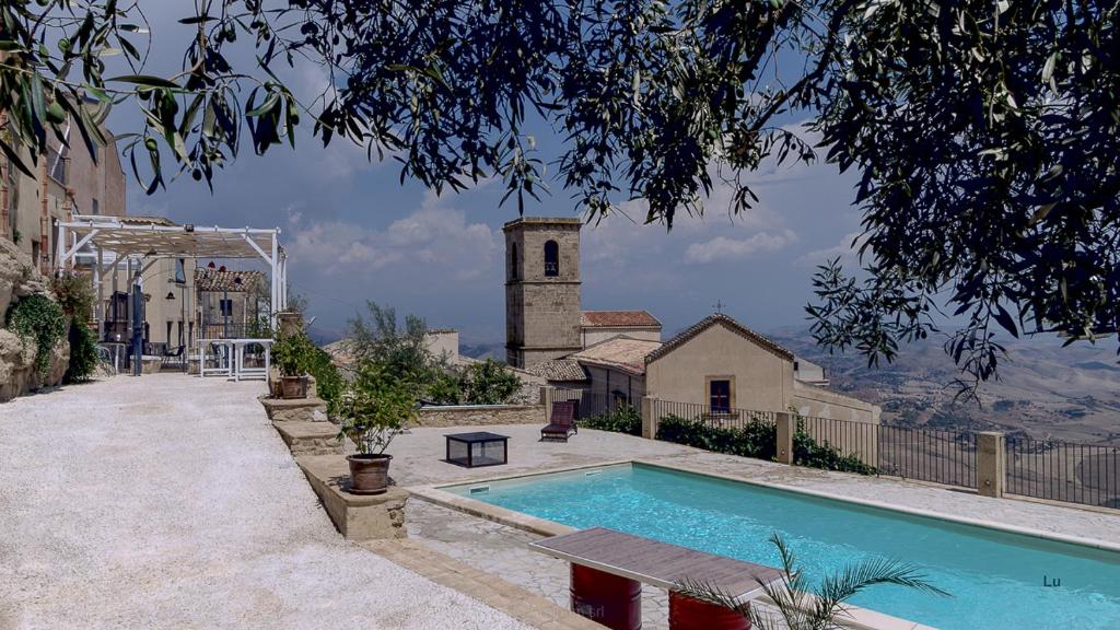 a house with a swimming pool and a church at Case al Borgo-Agira Centre-Home Relais in Agira