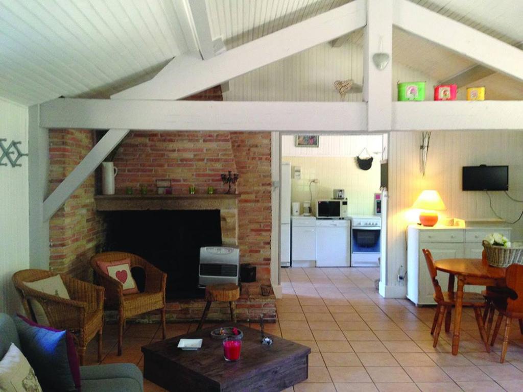 a living room with a fireplace and a kitchen at Gîte Péchot in Luxey