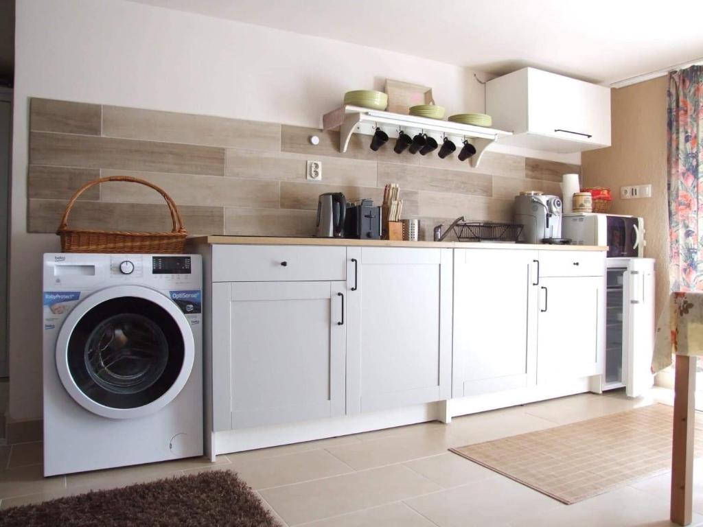 a kitchen with a washing machine in a kitchen at Orchidea Apartman in Csopak