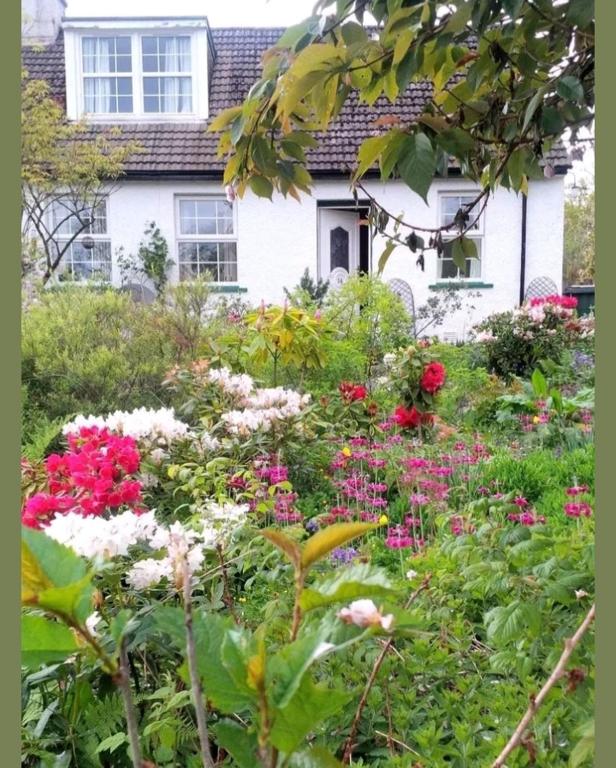a garden with flowers in front of a house at Argyllholidaycottage Loch Awe in Eredine