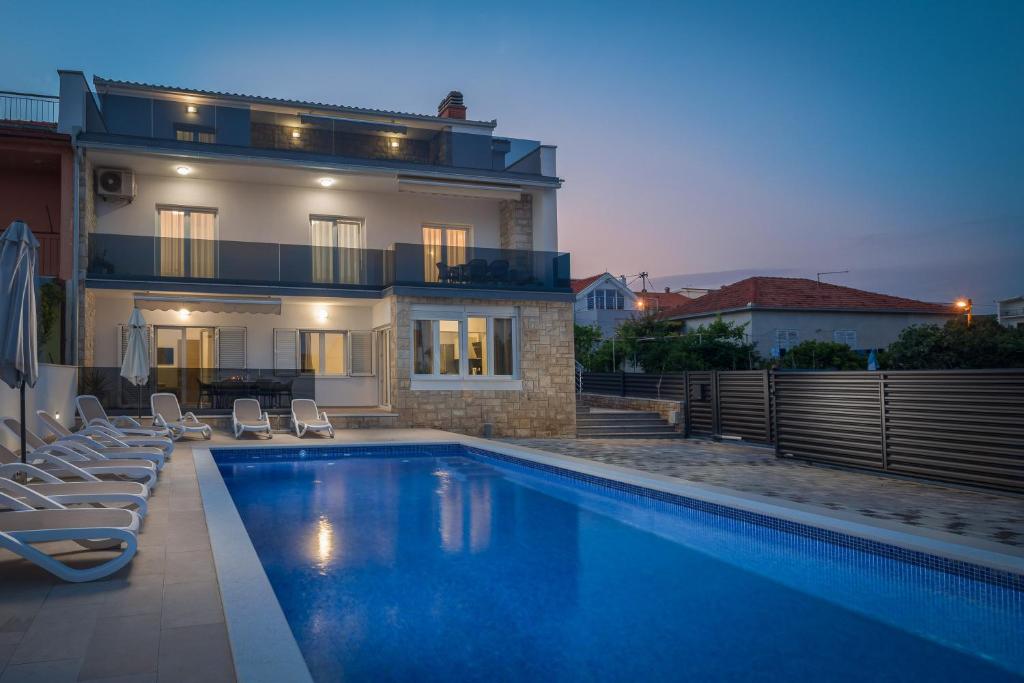 a villa with a swimming pool in front of a house at Apartments Apollo in Trogir