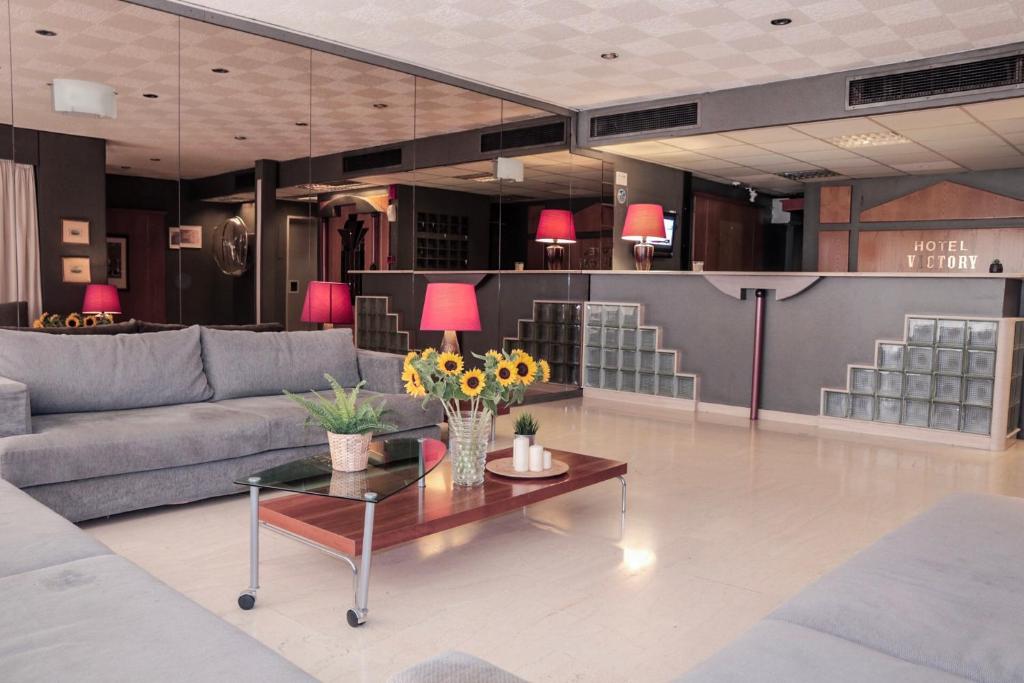 un soggiorno con divano e tavolo con fiori di Hotel Victory ad Atene