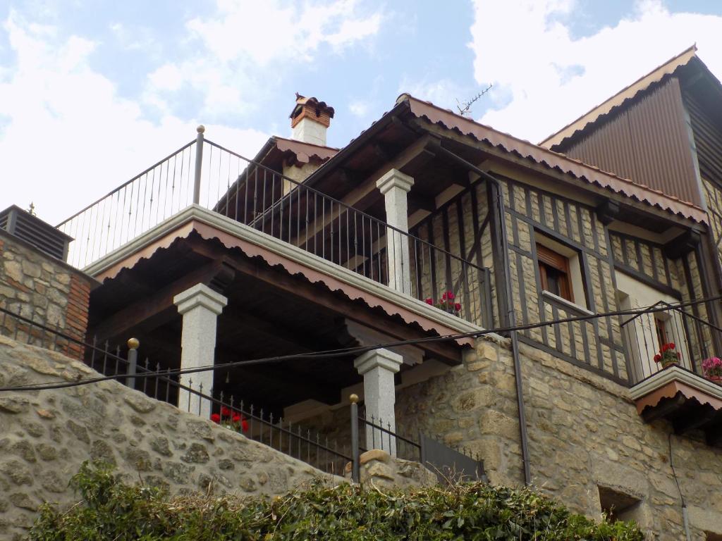 Una casa con balcón y un perro encima. en Casa Rural Generoso en Madroñal