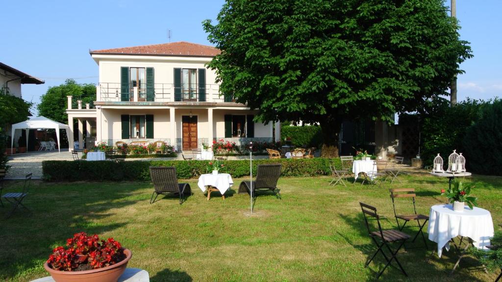 een huis met een tafel en stoelen in de tuin bij VILLA LE ROSE in Cavour