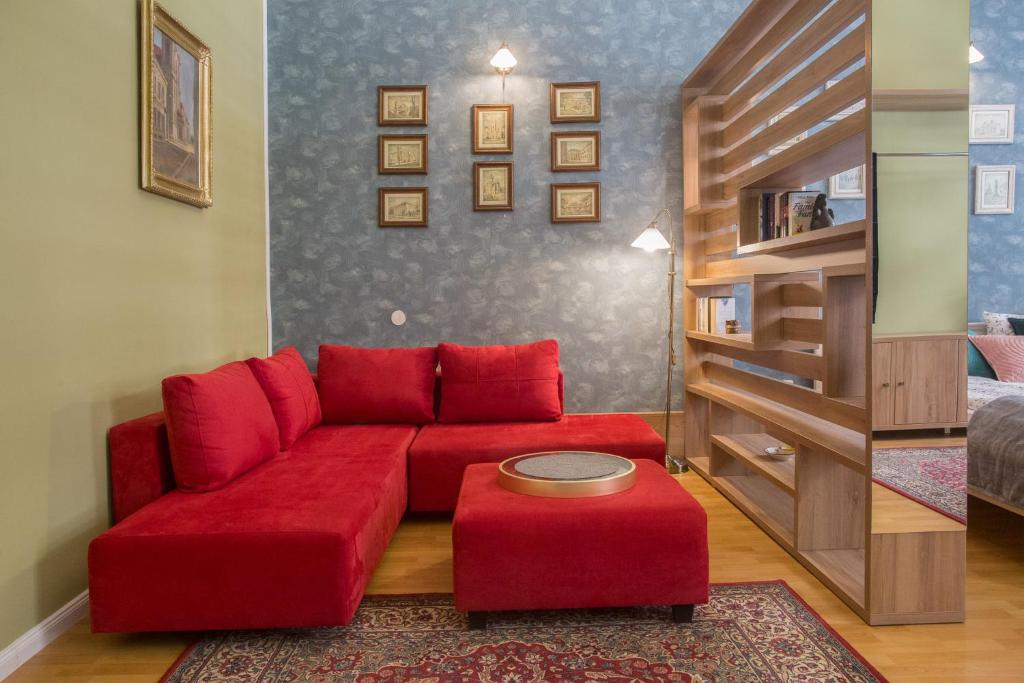 uma sala de estar com um sofá vermelho e um banco vermelho em City Light Apartment em Timişoara