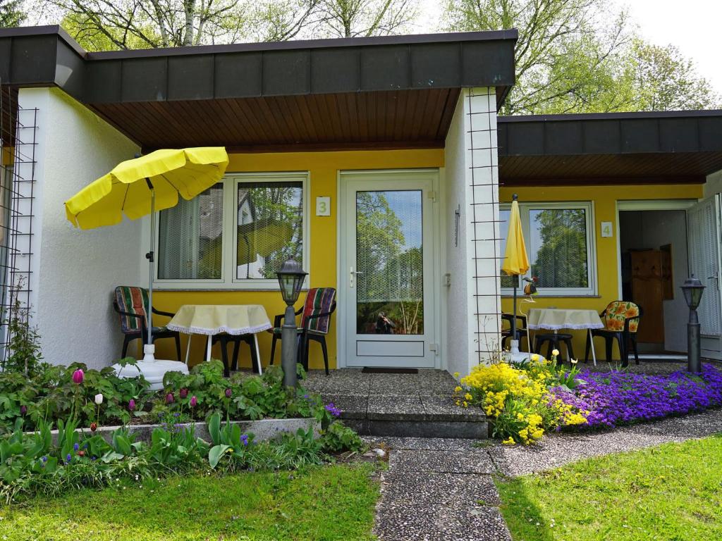 a yellow house with a table and chairs and flowers at Ferien-Oase Bad Dürrheim in Bad Dürrheim