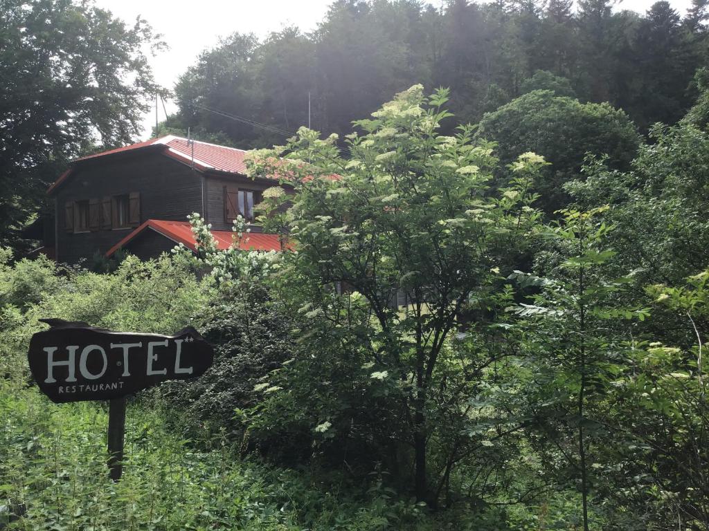 um sinal em frente a uma casa na floresta em HÔTEL RESTAURANT LA FOURMI em Bourbach-le-Haut