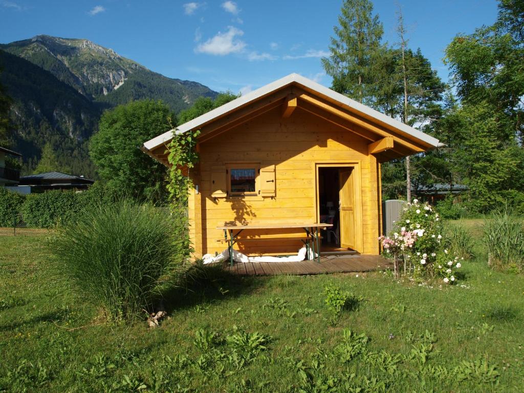 a small yellow shed with a bench in a field at Petra's Urlaubshüttn in Hermagor