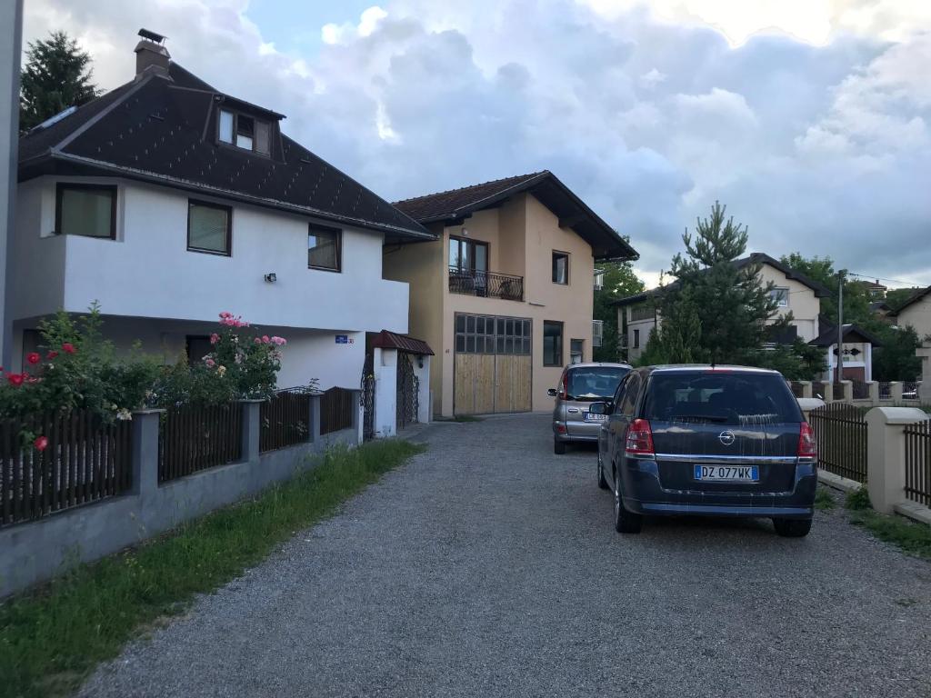 dos autos estacionados frente a una casa en Lav Apartments, en Bihać