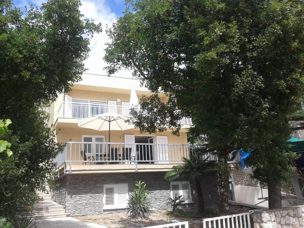 une maison jaune avec un balcon et un parasol dans l'établissement Apartment Nikica (with sea view, garden, parking), à Selce