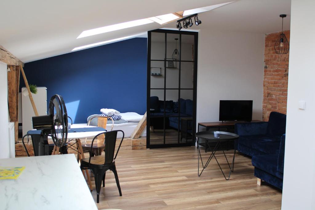 sala de estar con pared azul, mesa y sillas en Planty Gardens Apartments en Cracovia