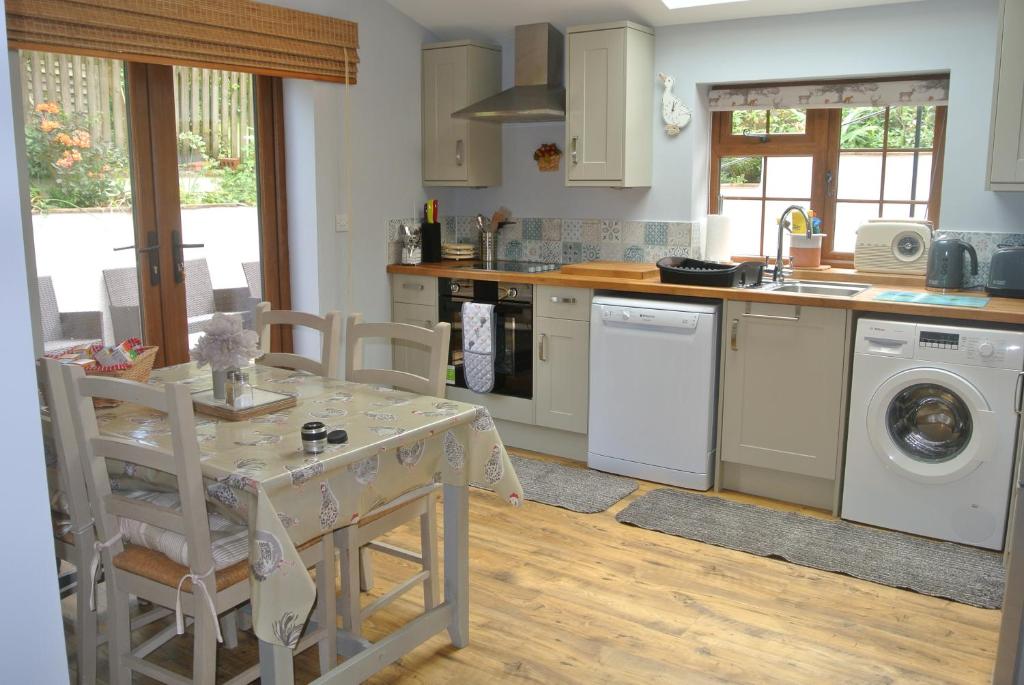 a kitchen with a table and a sink and a dishwasher at Higher Brockwell Annexe in Wootton Courtenay