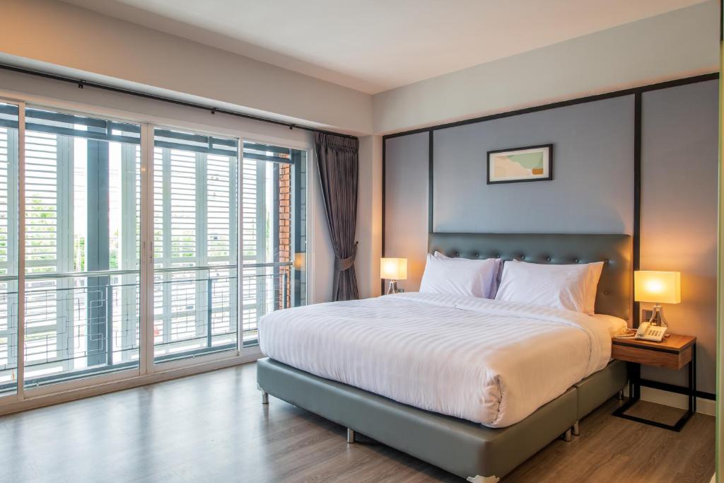 a bedroom with a large bed and large windows at Mayson Place Hotel in Ban Phraek Sa