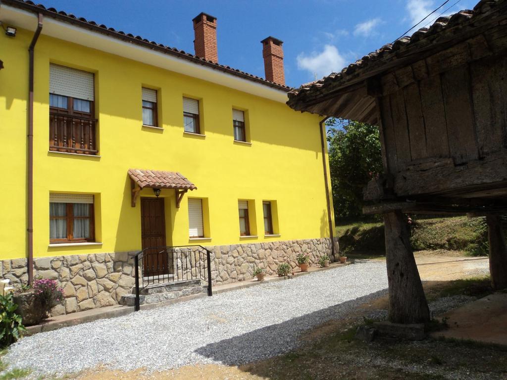a yellow house with a gate and a building at Apartamentos Rurales Pernús in Colunga