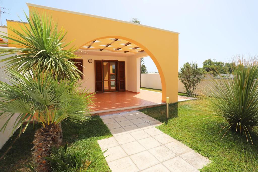 a house with an archway and palm trees in the yard at Villetta Mirtillo by TerraSalento in Torre dell'Orso