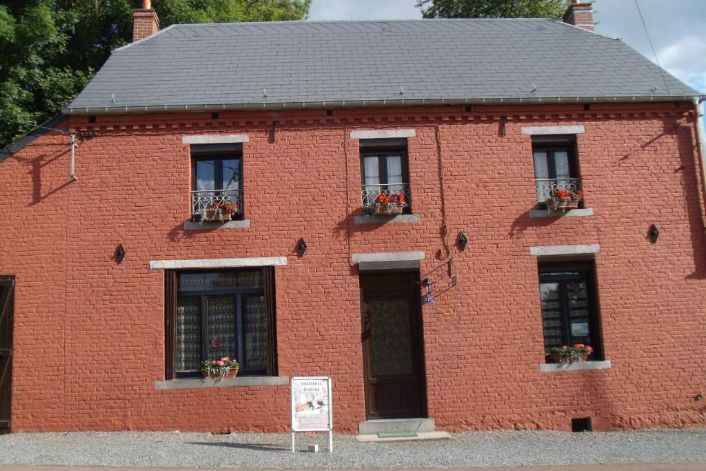 un bâtiment en briques rouges avec des fenêtres et un panneau devant dans l'établissement "A la douane", à Hestrud