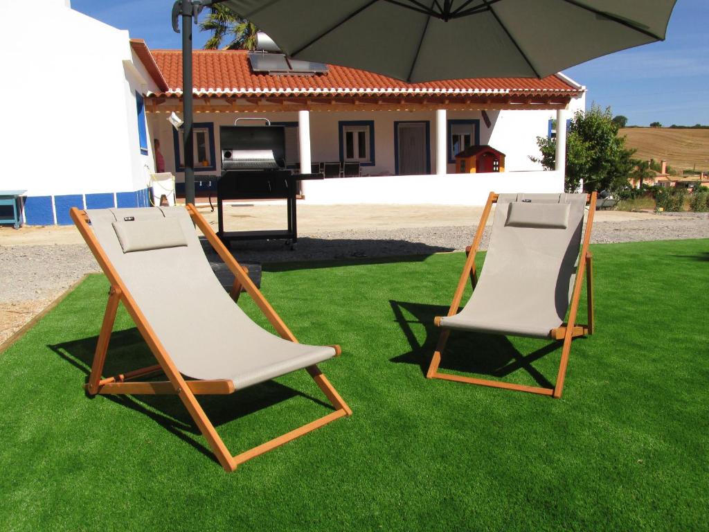due sedie da giardino sedute sull'erba sotto un ombrellone di Casa do Chaparral campo e praia a Cercal