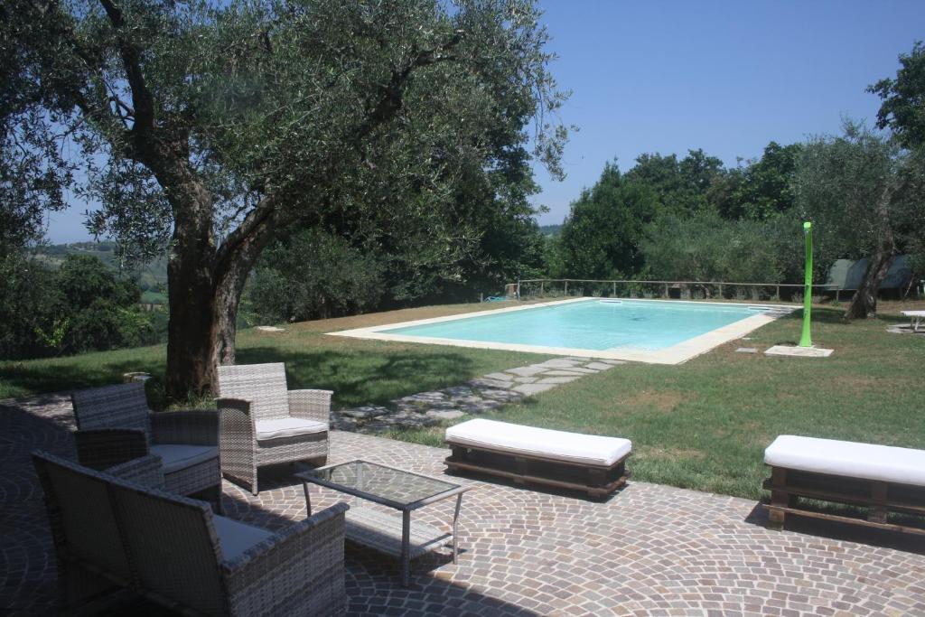 a swimming pool with chairs and a table next to a tree at Antica Fonte holiday home in Tavullia