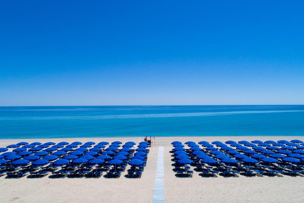 um grupo de guarda-sóis azuis na praia em Cala Luas Resort em Cardedu