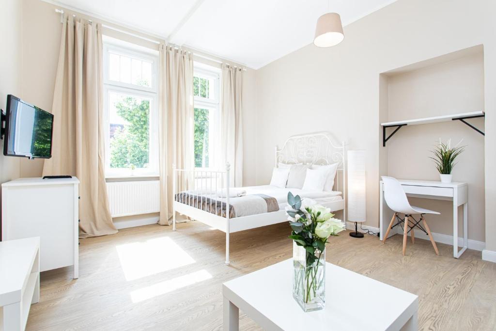 a white living room with a bed and a table at Riviera Rooms in Sopot