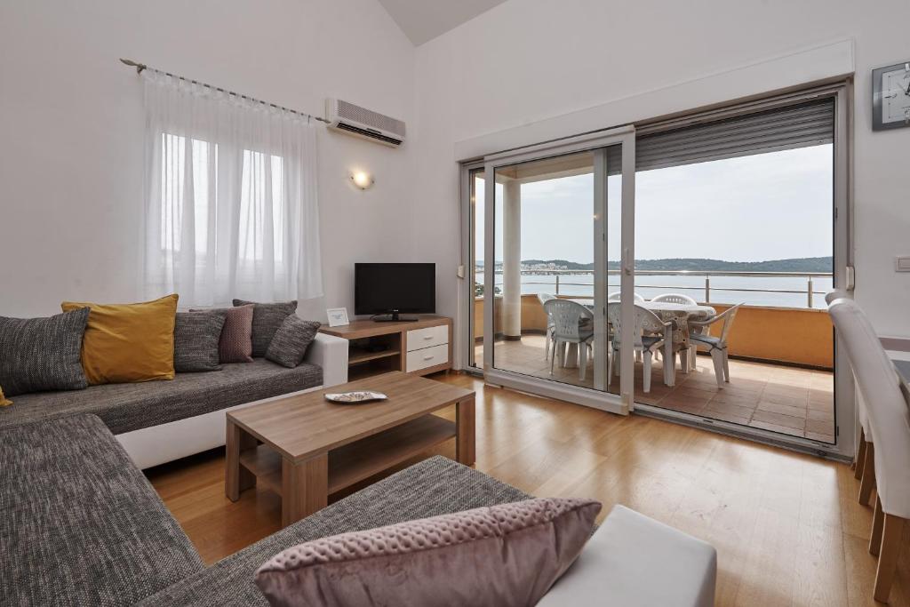 ein Wohnzimmer mit einem Sofa, einem TV und einem Tisch in der Unterkunft Buonocore apartment in Trogir