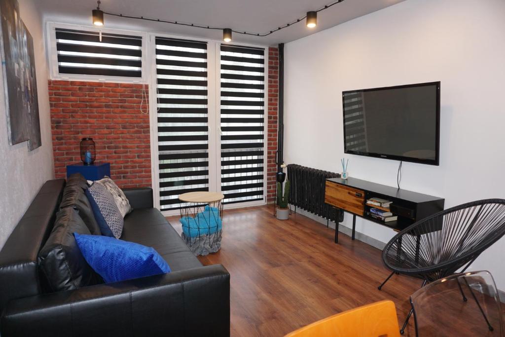 ein Wohnzimmer mit einem Sofa und einem Flachbild-TV in der Unterkunft Apartament metro rondo Onz in Warschau