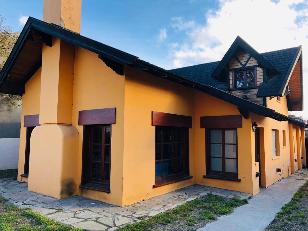 a yellow building with black windows and a roof at Hostel Olimpo House in San Carlos de Bariloche