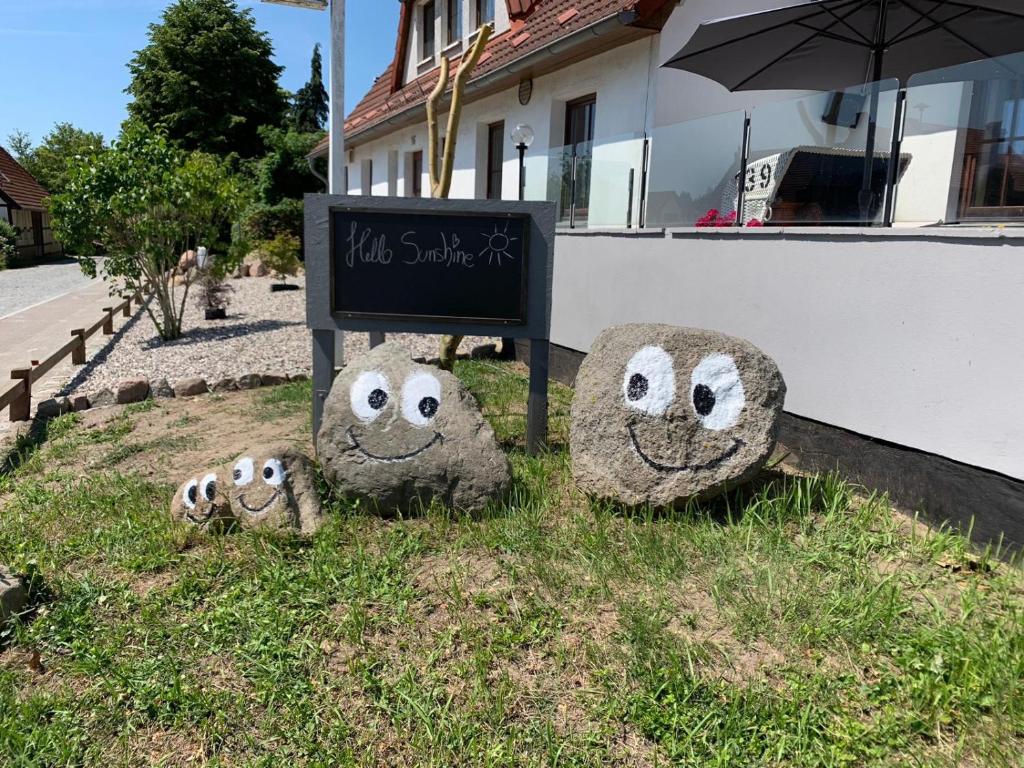 three large rocks with faces painted on them next to a sign at Gasthof Ostwind - ferienwohnungen & meer in Steffenshagen