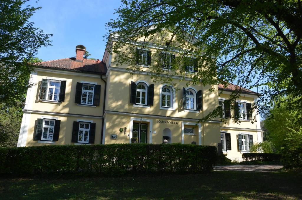 una gran casa blanca con un árbol delante en Louisenvilla, en Bad Gleichenberg